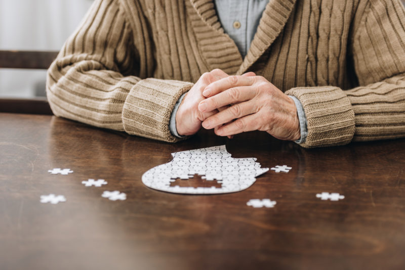 Can Dementia Be Prevented? ; cropped view of retired man playing with puzzles on table