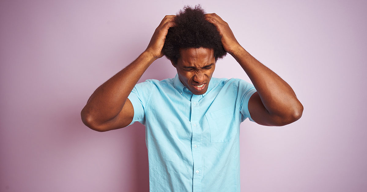Young american man with afro hair wearing blue shirt standing over isolated pink background suffering from headache desperate and stressed because pain and migraine. Hands on head; blog: Are There Different Types of Migraine?